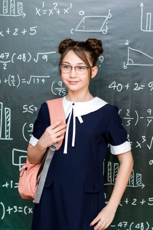 Teenage Girl with School Bag Standing at the Blackboard Portrait of a schoolgirl 10 - 12 years old.