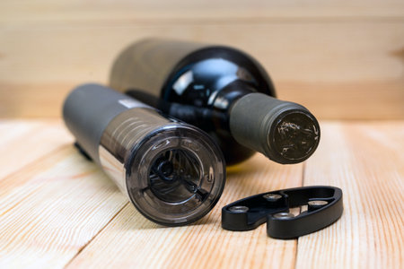 Electric corkscrew wine bottle and film opener on a light wood background.