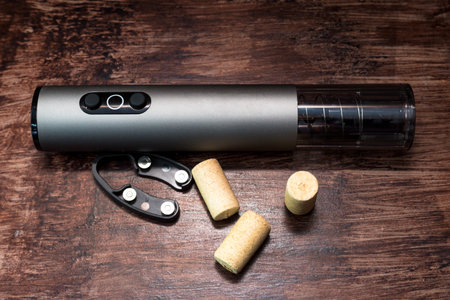 electric corkscrew and wine bottle caps lie on a dark wood table, preparing for the holiday.