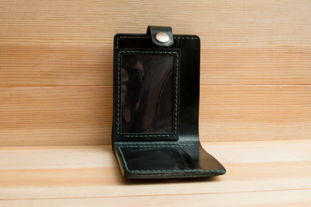 Men's wallet made black leather on light wood, Shooting for the catalog.