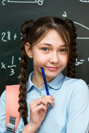 Girl student chatting with a pen, bringing it to her face.の写真素材