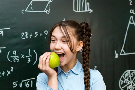 Girl bites apple, vegetarian food at school.