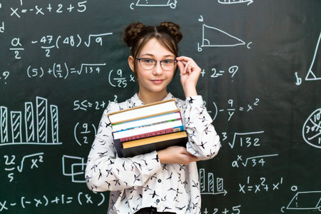 Schoolgirl girl in vision glasses a white blouse with books in her hands.の写真素材
