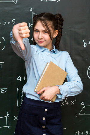 Schoolgirl girl shows her dissatisfaction with school curriculum putting her finger down.