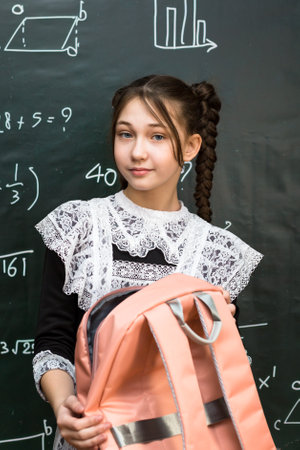 Portrait of a schoolgirl with a school bag on her shoulder, a student with a bag standing...