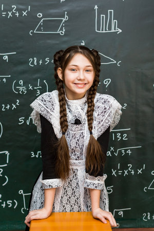Schoolgirl in school uniform with white apron, festive clothes for school graduation.