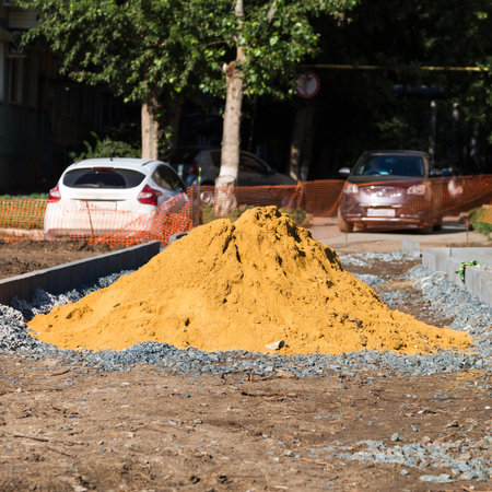 Pile of yellow sand on the construction of a pedestrian sidewalk.の写真素材