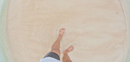 Vacation on ocean beach, feet on sea sand