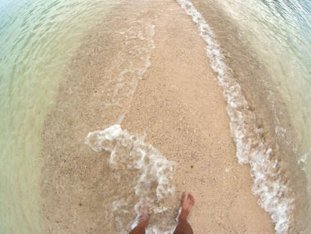waves and naked feet on a sand beachの写真素材