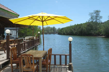 the chair under long umbrella near riverの写真素材