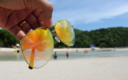 Hand holding colorful sunglasses against and blue sunny skyの写真素材