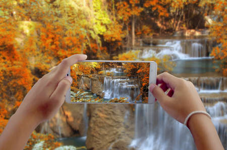 Travel concept, take photography waterfall in autumn forest at Huai Mae Khamin waterfall National park Kanchanaburi Thailand by phoneの写真素材