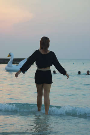 Woman on sandy beach in sunset leavingの写真素材