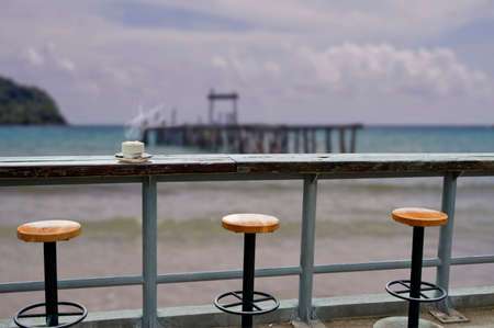 coffee shop on the beach and coffee cup over wooden table