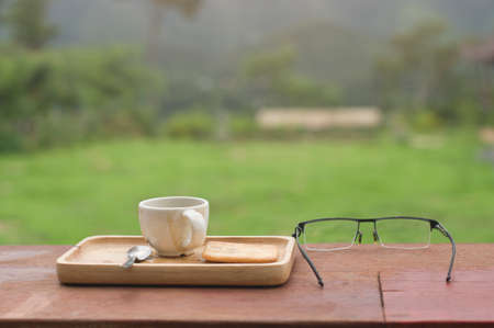 cup of coffee and eyeglasses on a vintage wooden table in nature