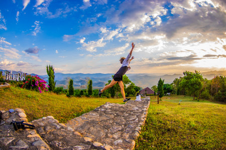 Young woman practicing yoga on the top of the mountain at sunset.の写真素材