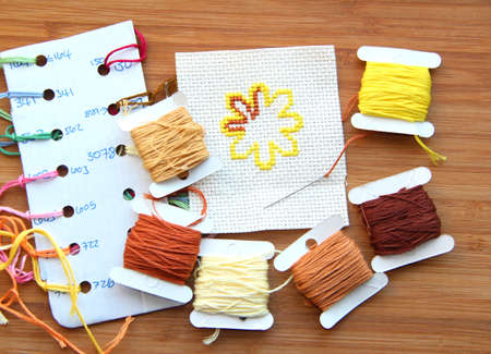 Cross-stitch set  colour palette, threads, canvas against a wooden backgroundの写真素材
