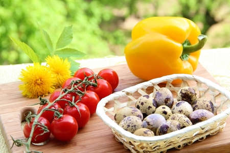 A composition of quail eggs and fresh vegetables  pepper and cherry tomatoes  on wood の写真素材
