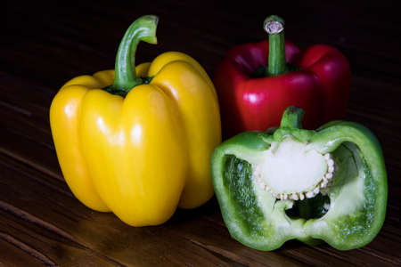 Three bell peppers with one sliced in halfの写真素材
