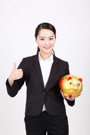 A business woman carrying a piggy bankの写真素材