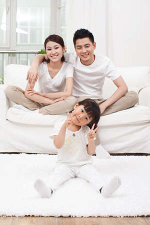 Young Chinese girl in a living room with parents in the backgroundの写真素材