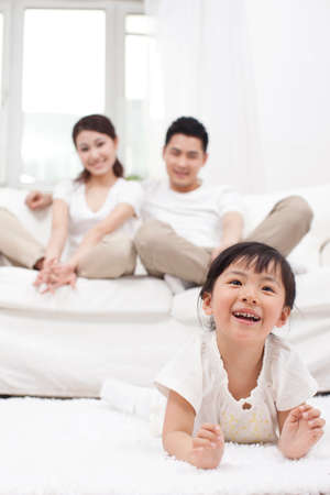 Young Chinese girl in a living room with parents in the backgroundの写真素材