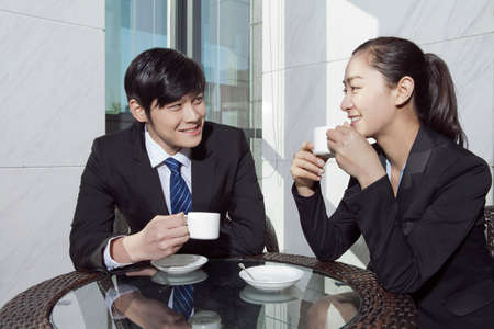 Businessman and businesswoman drinking coffee in officeの写真素材