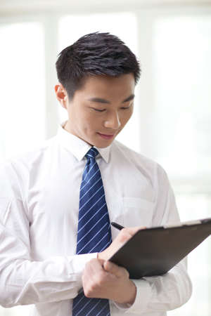 Portrait of young businessman writing in office,close-upの写真素材