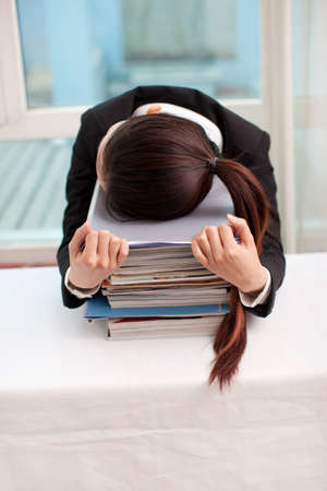 Young woman sleeping at desk with files