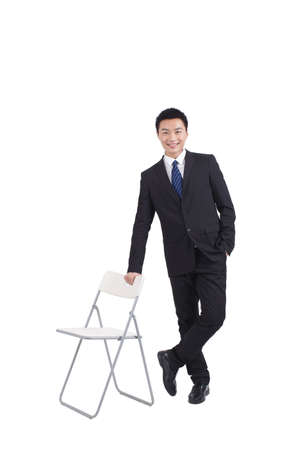 Portrait of young businessman standing near chair,relaxingの写真素材