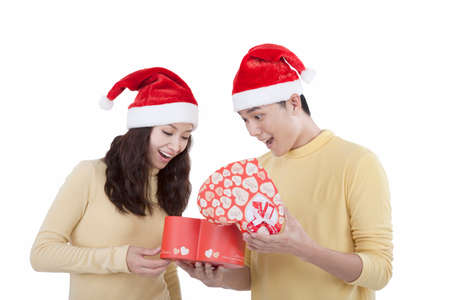 Portrait of a young couple wearing Santa hats holding gifts