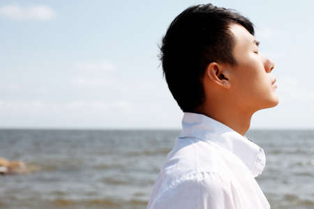 Young man standing on the seasideの写真素材