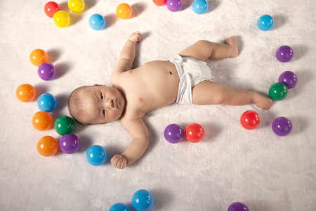 A baby boy surrounding by color ballsの写真素材
