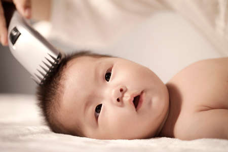 Mother shaving hair of the baby