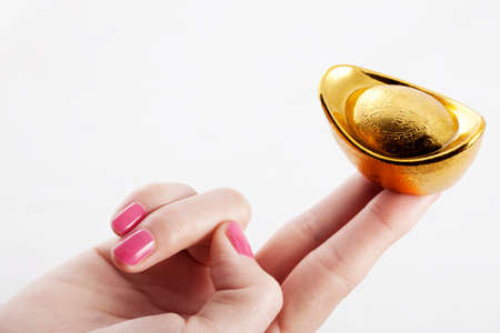 Two fingers on a gold ingotの写真素材