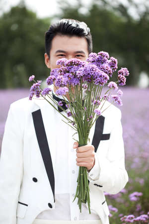 The groom holding a bunch of lavender flowersの写真素材