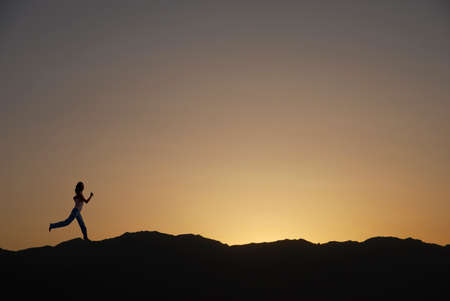 A woman is running in silhouetteの写真素材