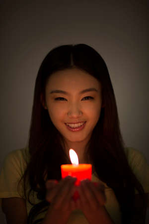 Young woman holding a red candleの写真素材