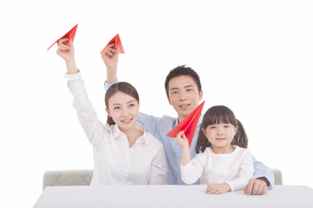 Portrait of daughter playing paper planes with parents high quality photoの写真素材