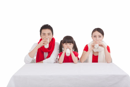 Portrait of daughter with parents drinking milk,sitting at deskの写真素材
