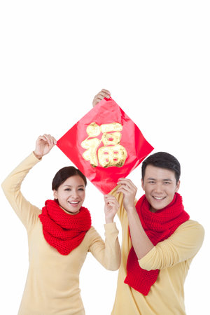 Portrait of young couple holding a Chinese Good Luck Fu,paying New Year callの写真素材