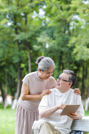 Happy elderly couples use tablet computers in the parkの写真素材