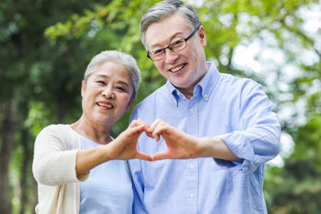 Portrait of happy old couple with Heart gesture