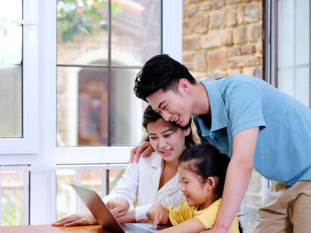 Happy family of three using laptop in the house