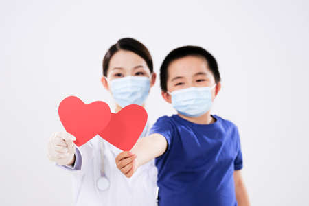 A woman doctor and a little boy each had a red heart looking at the cameraの写真素材