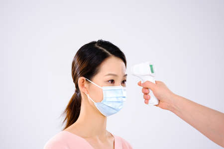 A young lady with a mask took her temperature side view