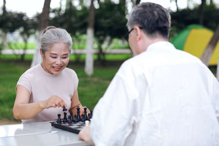 Happy old couple playing chess in the park high quality photo