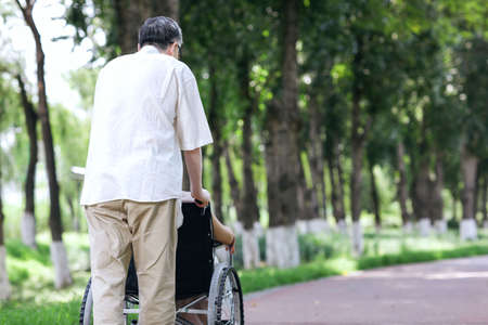 The old man pushes his wife in a wheelchair high quality photoの写真素材