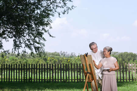 Happy old couple painting in the park high quality photoの写真素材