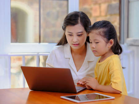 Happy mother and daughter use laptops high quality photo